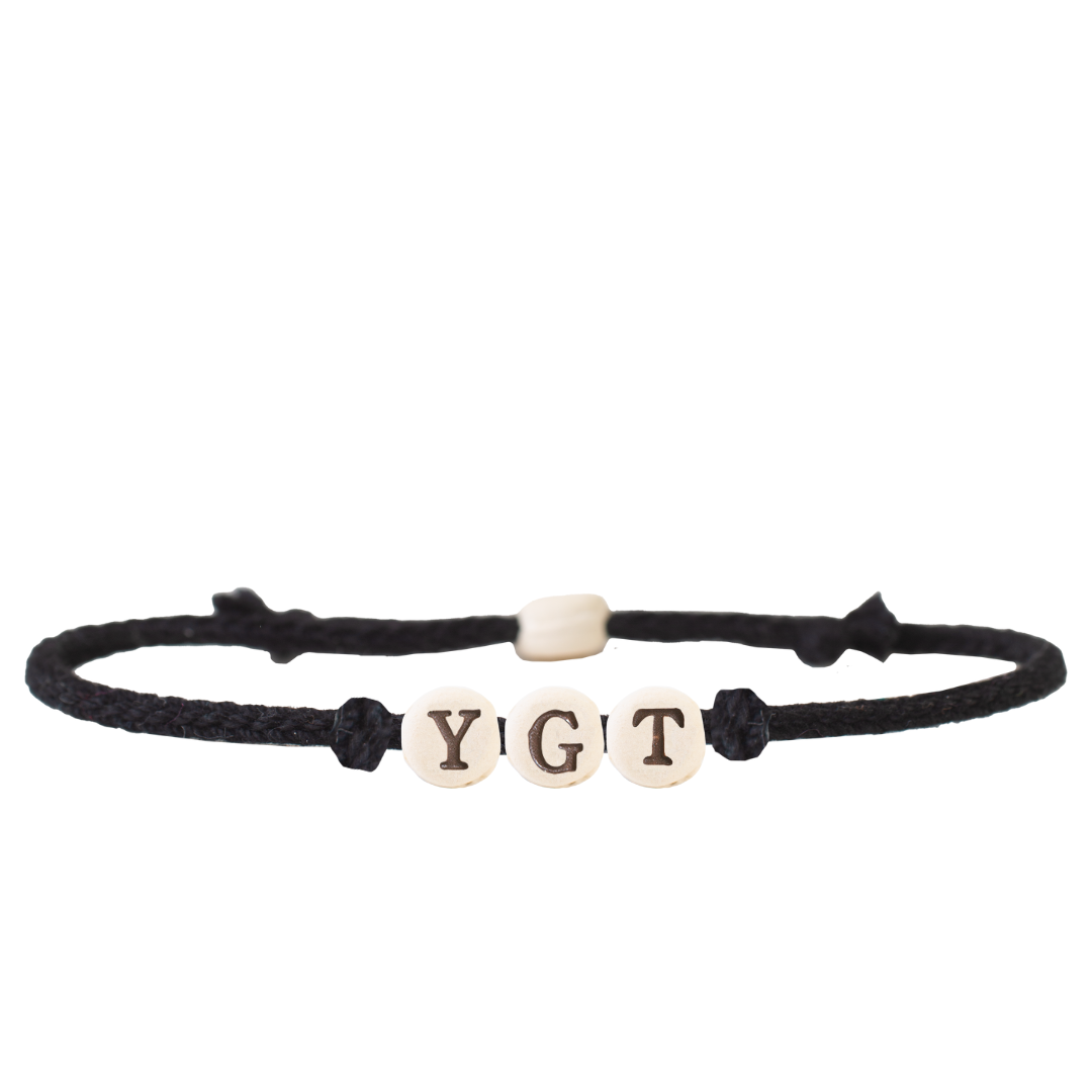 The Joni x MudLOVE Friendship Bracelet 4-Piece Set featuring a black cord bracelet with beads spelling &