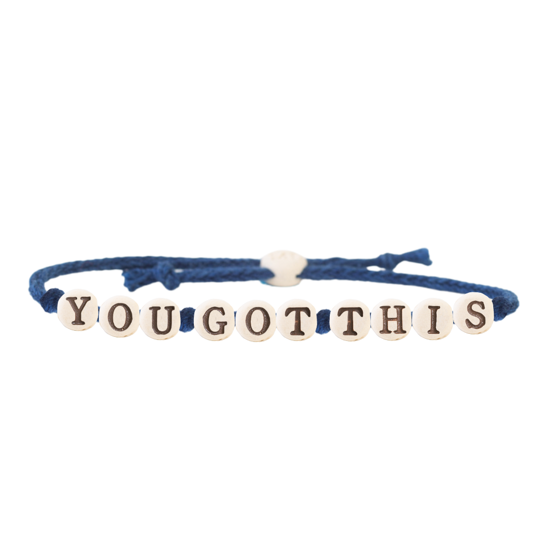 The Joni x MudLOVE Friendship Bracelet 4-Piece Set displaying a blue cord bracelet with beads spelling &