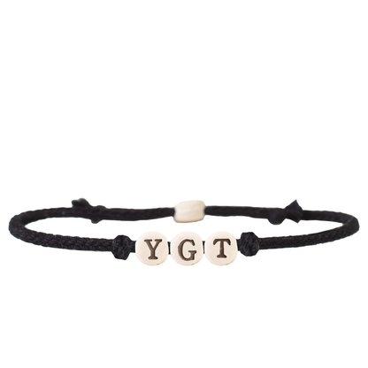 The Joni x MudLOVE Friendship Bracelet 4-Piece Set featuring a black cord bracelet with beads spelling &